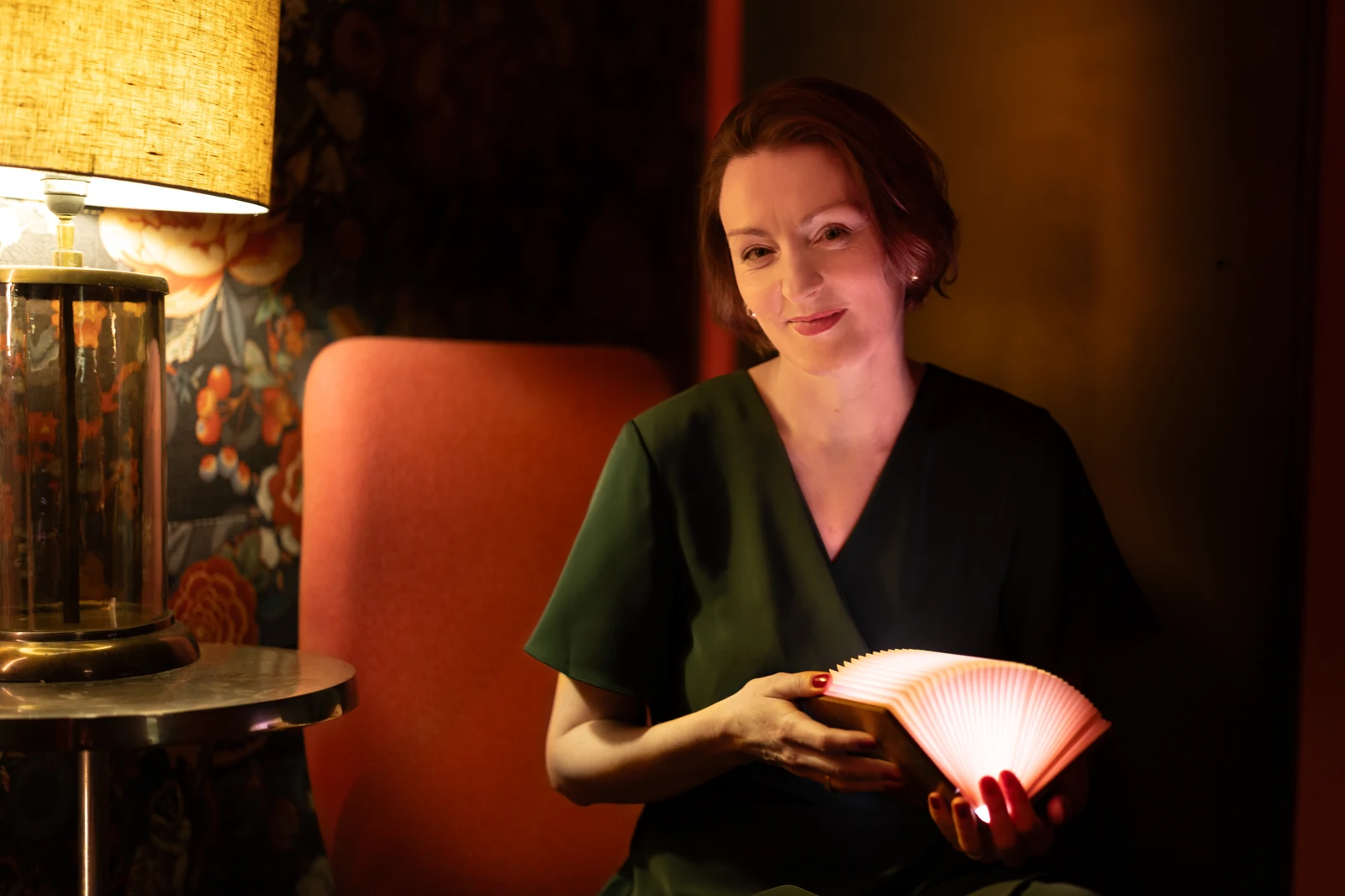 Marie-Luise Steiner holding an illuminated book in warm lamplight — storyteller portrait